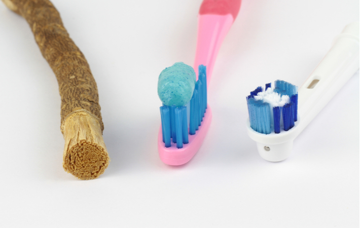 historical toothbrushes ranging from a stick to a plastic toothbrush to an electric toothbrush