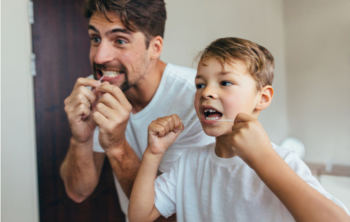 father and son flossing together in the bathroom