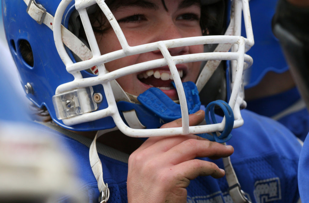 Teenage boy wearing a mouthgaurd while playing football.