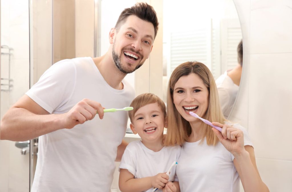 smiling family with healthy teeth brushing their teeth together