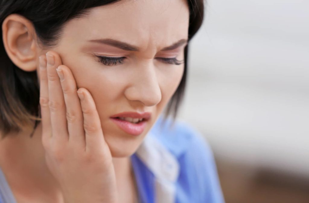 Woman experiencing jaw pain because of TMJ symptoms