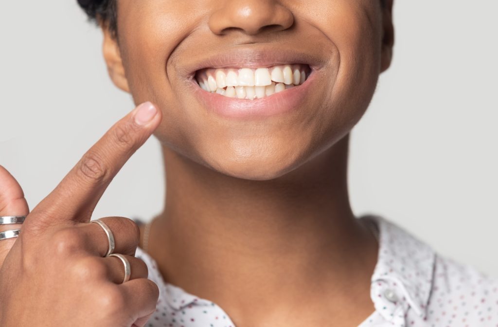 A woman pointing to her beautiful white smile showcasing her great oral hygiene