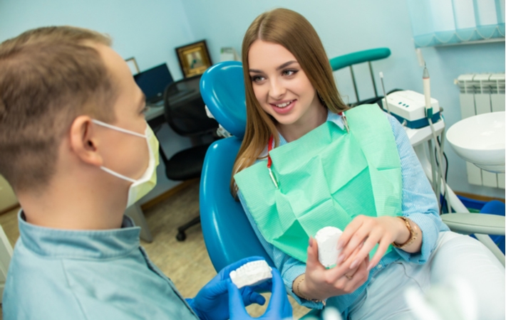  girl sitting in a dental chair discussing with her dentist about the possibility of using sedation for her procedure
