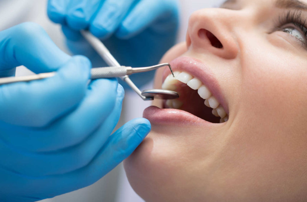 A close up of a patient having her teeth examined by a dentist due to a toothache