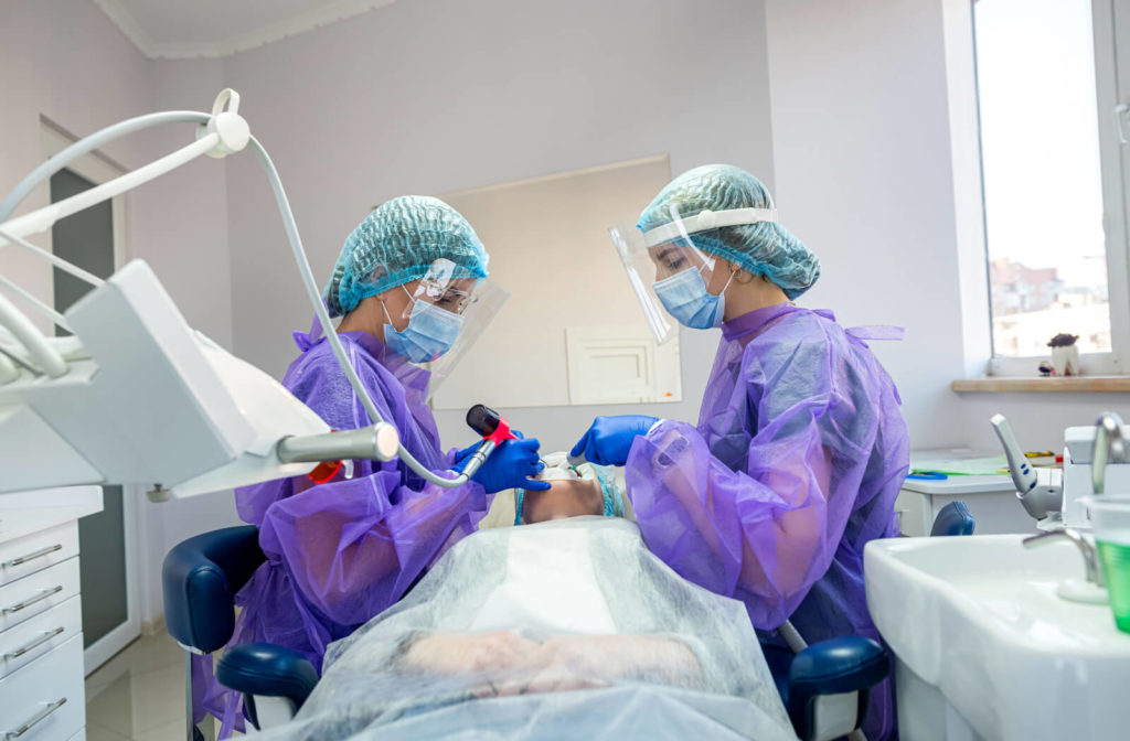 A surgical dentist and her assistant perform an operation to remove high wisdom teeth.
