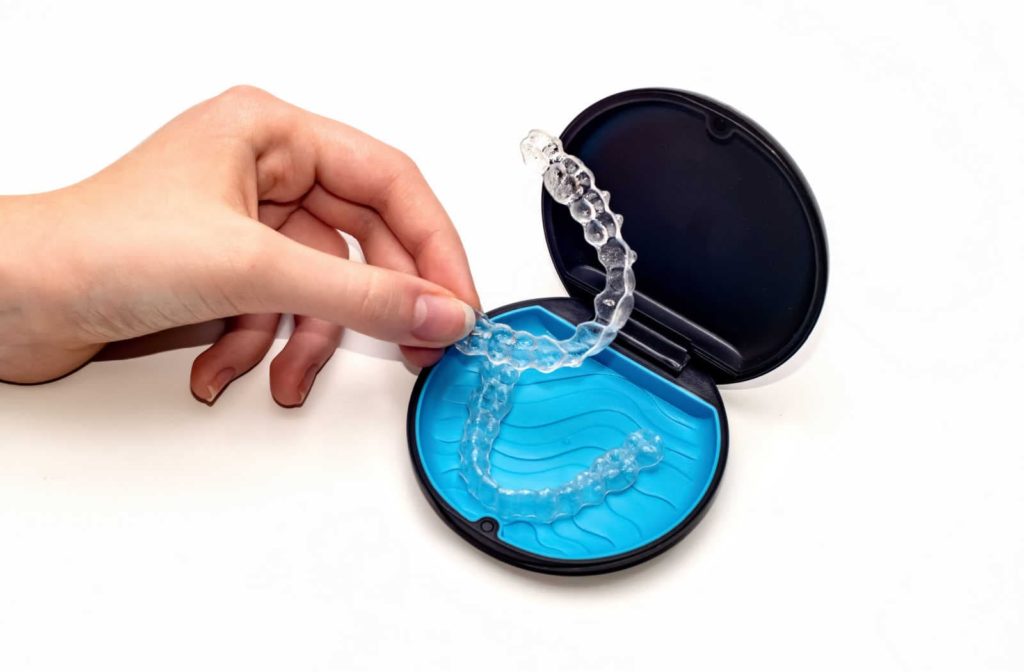 A hand putting Invisalign clear aligners in the case before eating food or chewing gum