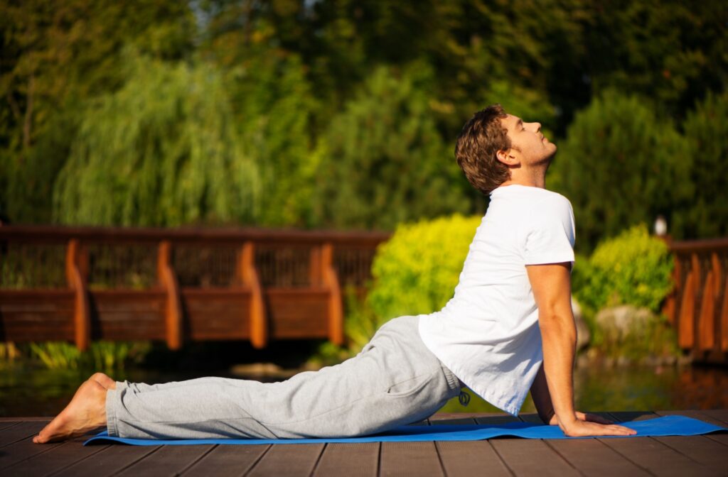 A man practising yoga outdoors; he is in a cobra pose.