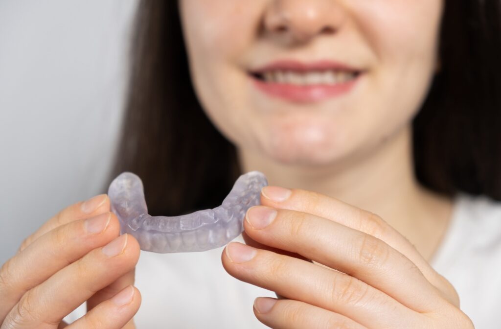 Close-up of a woman holding a mouthguard to treat TMJ.