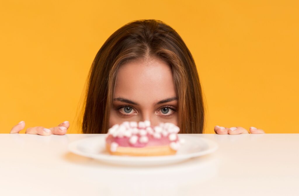 A person who has just had a dental cleaning looks over a counter and gazes at a donut.