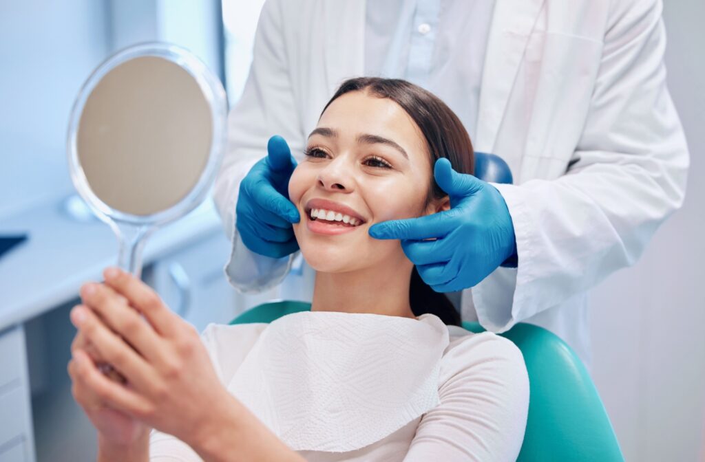 A dentist points at their patient's white smile in a mirror after a dental cleaning.