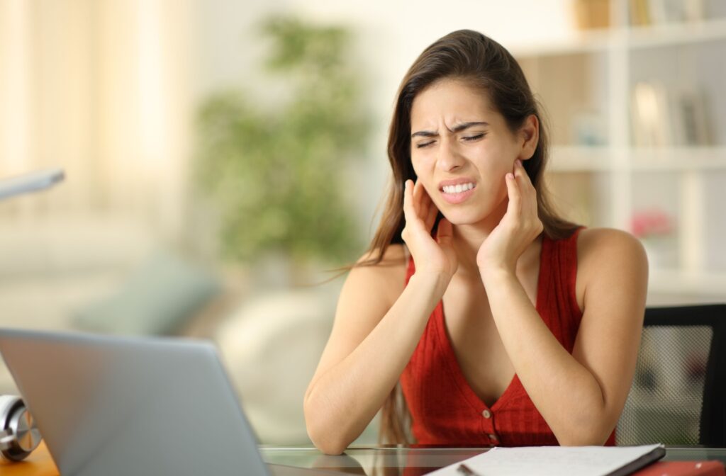 A person working at a desk rubs their sore jaw joint.