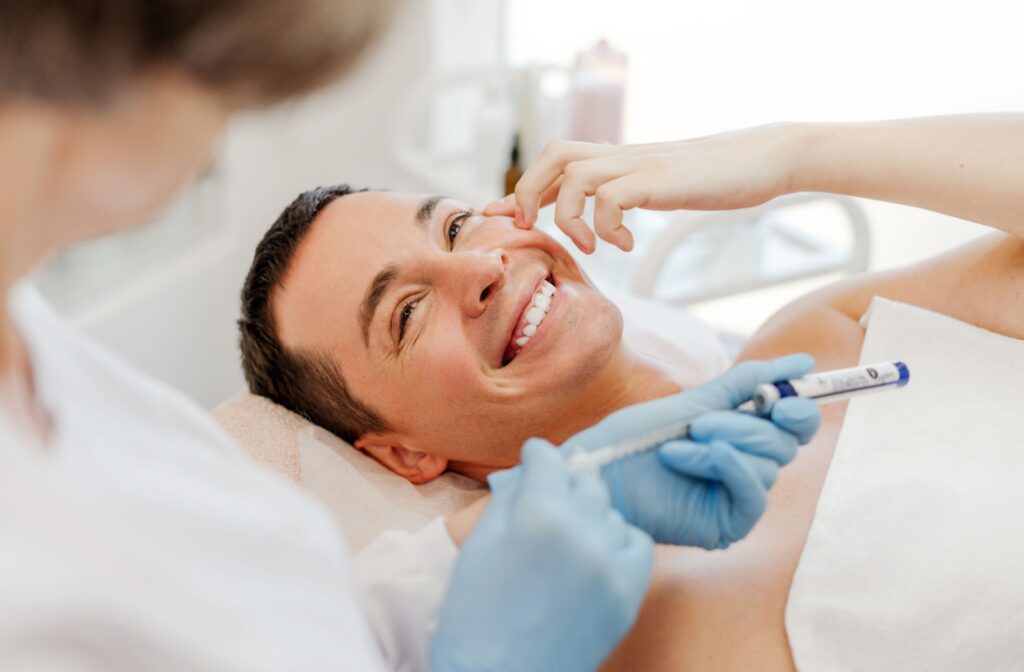A happy patient smiles as their dentist prepares a Botox injection.