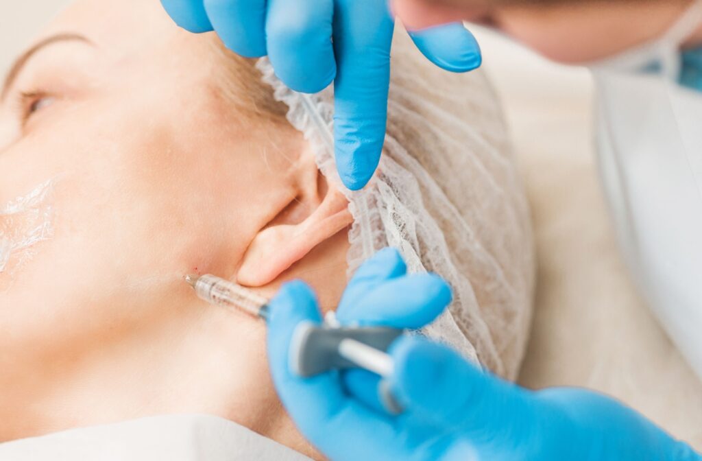 A close-up of a dentist carefully administering a Botox syringe into a patient's jaw to help relieve TMJ.