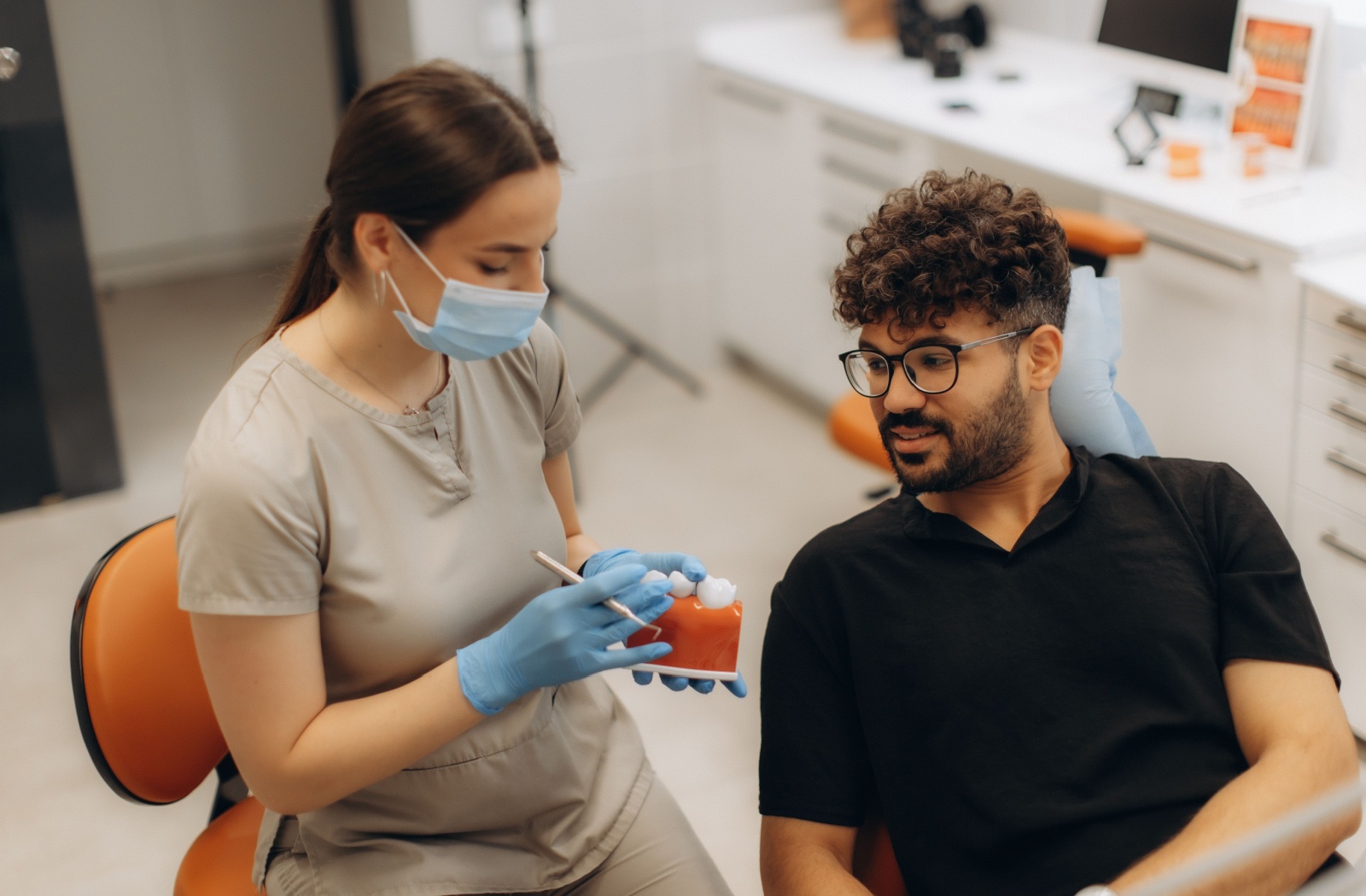 Person laying in a dentist chair while the dentist shows them dental crowns