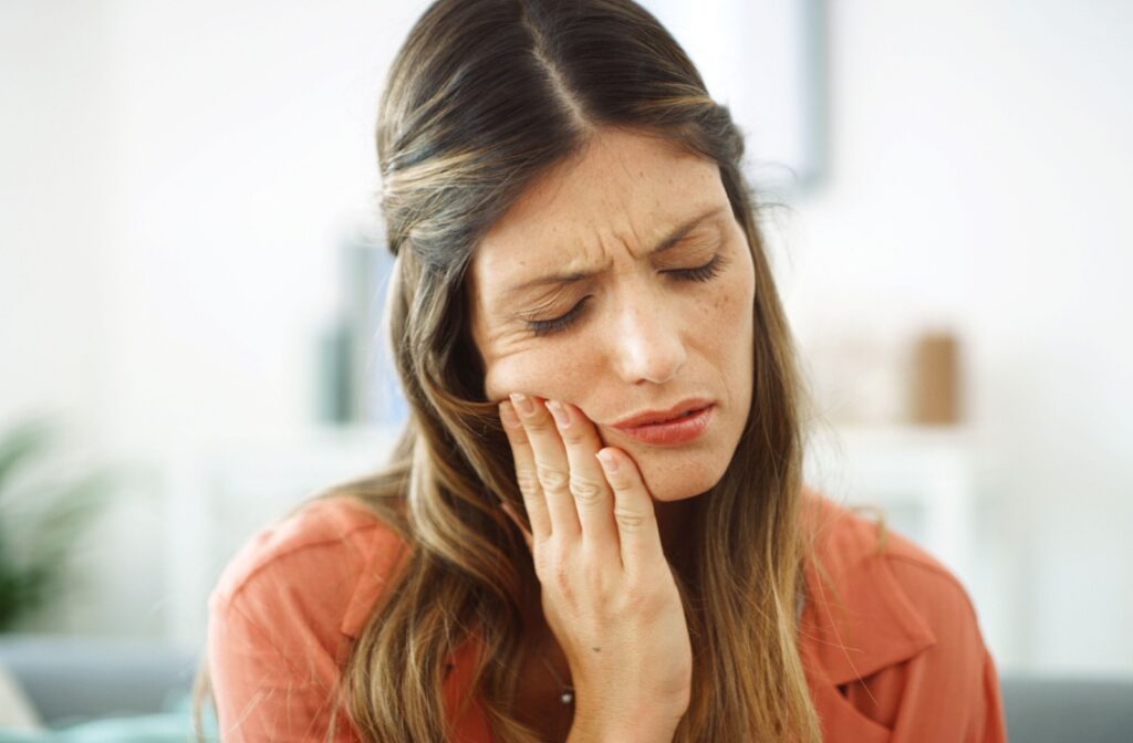 Woman rests her hand against her jaw after experiencing jaw pain.
