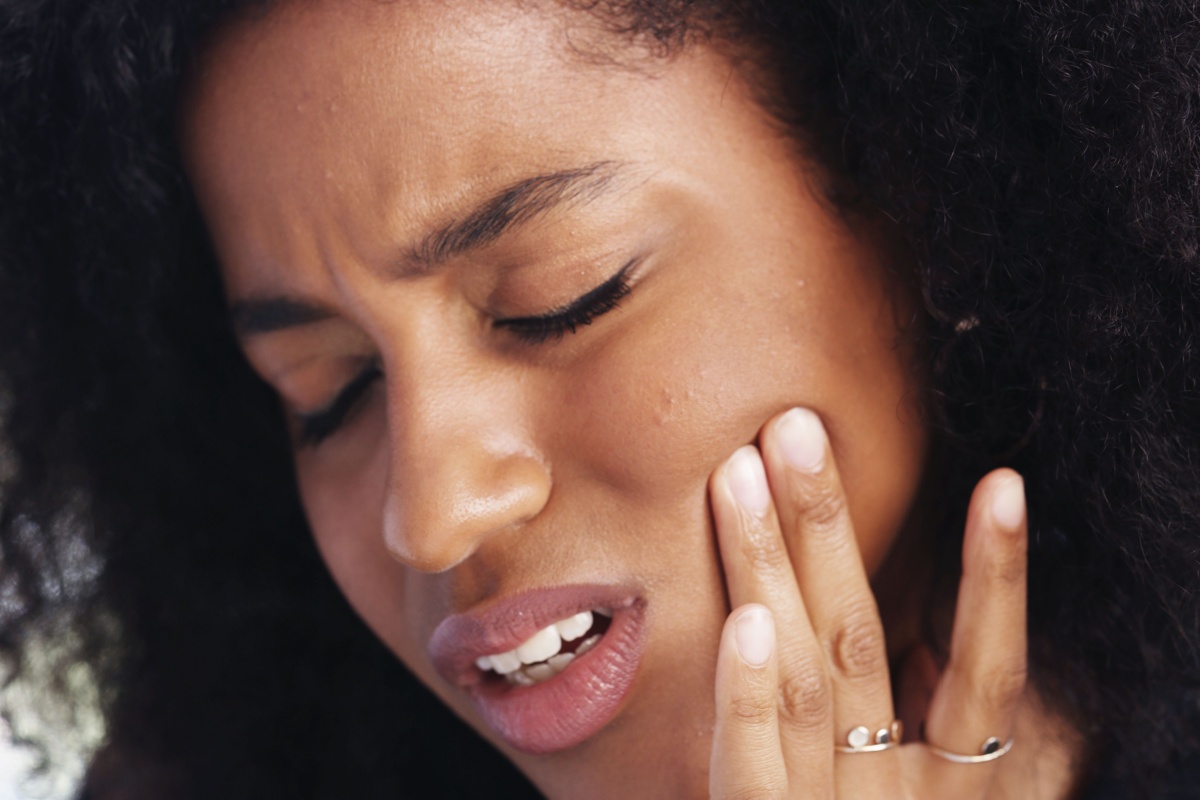 A person holding their jaw from pain caused by TMJ