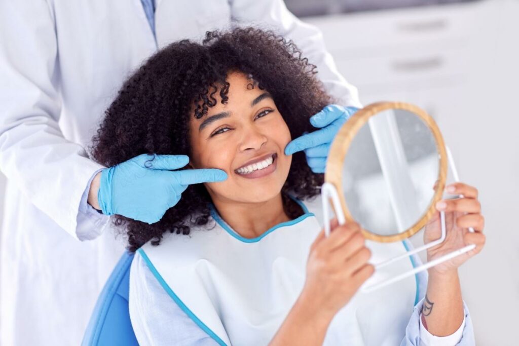 A dentist pointing to a persons perfect smile while they look in a mirror