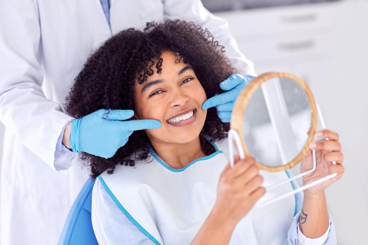 A dentist pointing to a persons perfect smile while they look in a mirror