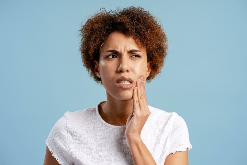 A person holding their jaw that is experiencing pain caused by a cavity