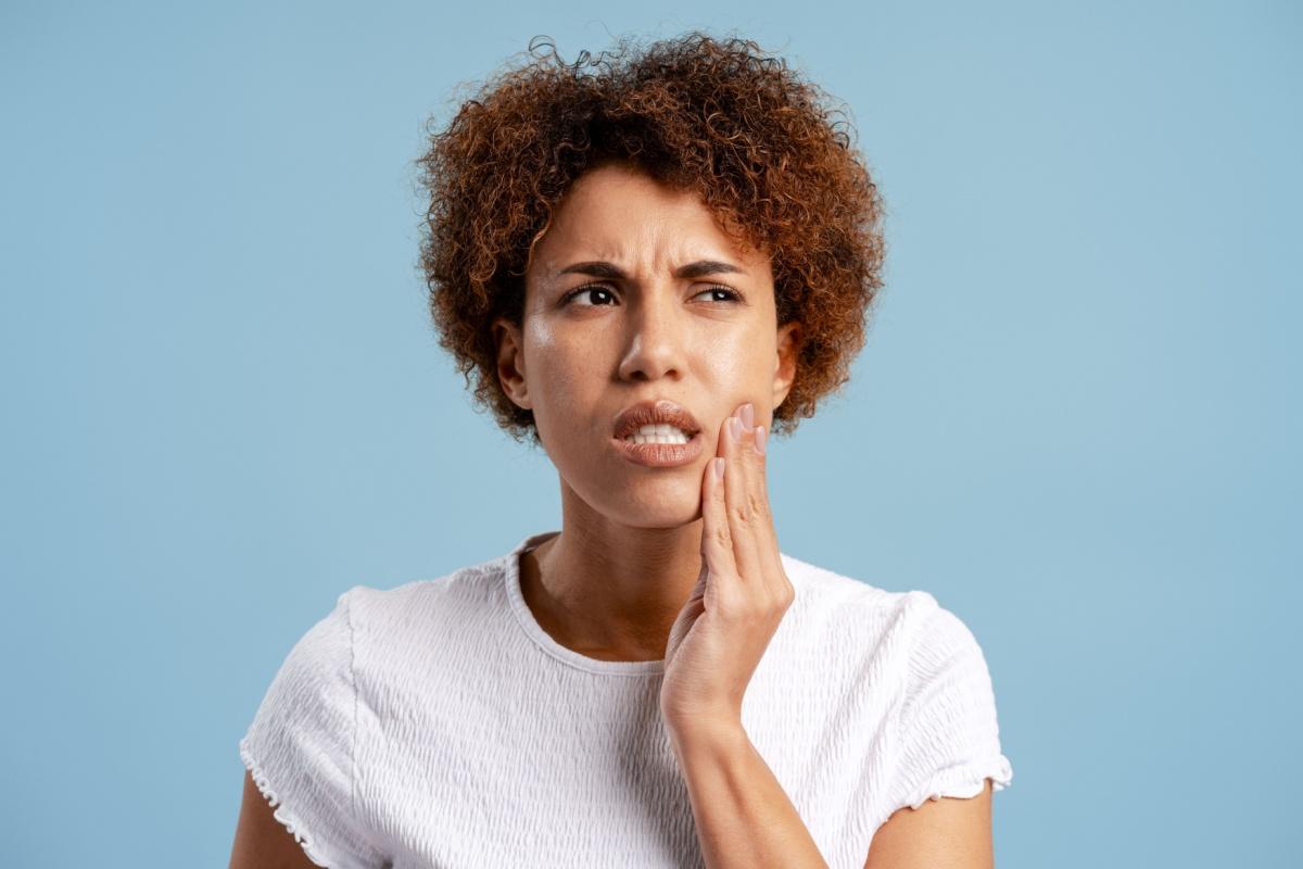 A person holding their jaw that is experiencing pain caused by a cavity